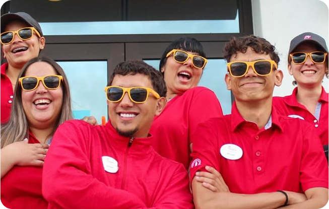 Varios Team Members juntos de pie afuera, con gafas de sol y sonriendo