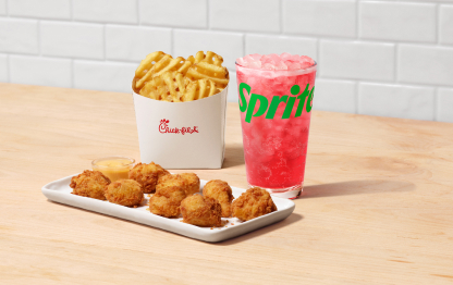 Nuggets Chick-fil-A® en un plato blanco con Strawberry Hibiscus y Sprite®, y Papas Fritas Waffle sobre una mesa, frente a una pared de azulejos